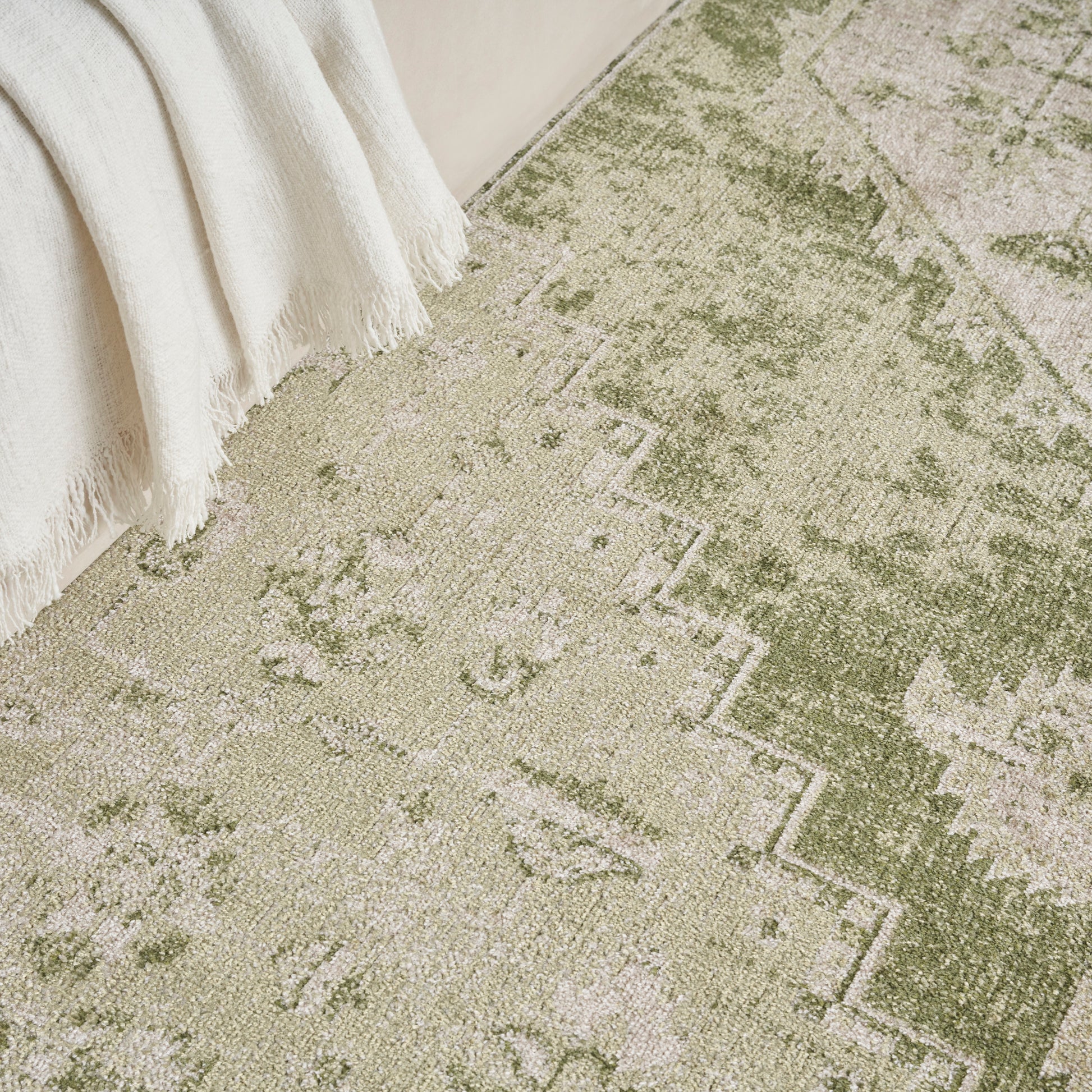 Rectangular vintage-inspired area rug in olive green and beige with geometric stepped border; soft, distressed look.