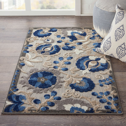 Blue and beige floral area rug on dark wood floor, beside a gray sofa with a patterned pillow.