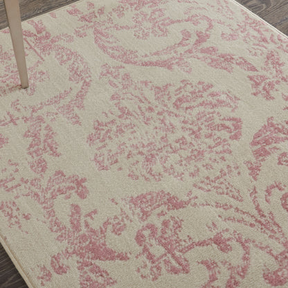 Beige rug with pink damask floral pattern; soft texture with wooden floor edge and table leg visible.