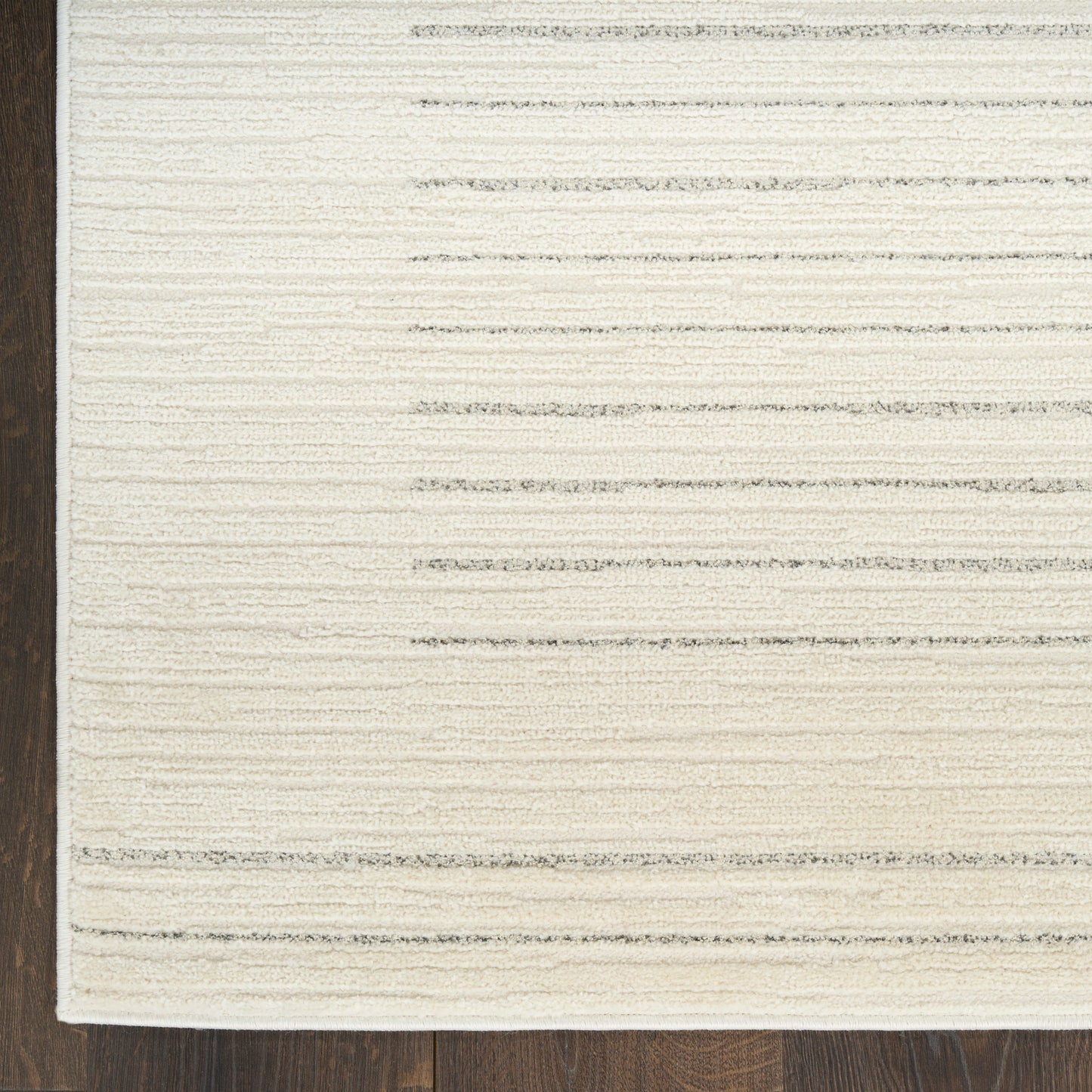 Cream area rug with subtle horizontal gray stripes on dark wooden floor.