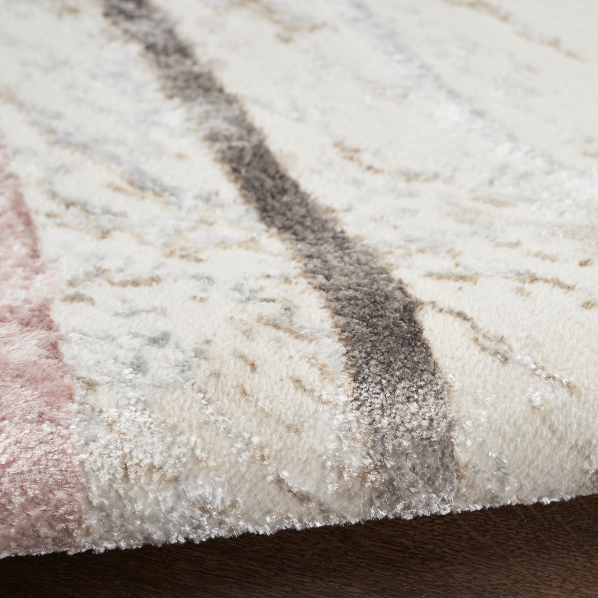 Cream shag rug with pink and gray stripes; close-up of plush pile and edge.