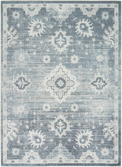Blue distressed area rug with white ornamental medallions, floral motifs, and a decorative border.