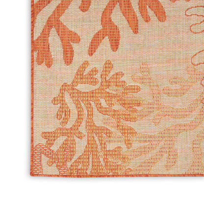 Close-up of peach textured woven rug with orange botanical damask pattern and orange edge binding.