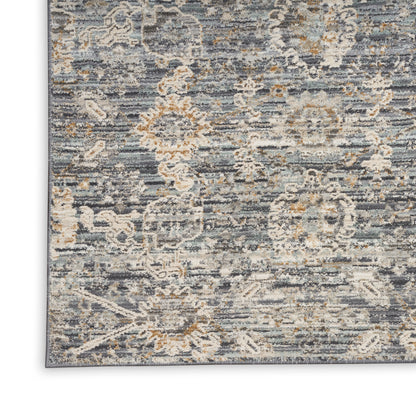Blue-gray oriental rug with cream and tan floral medallions, distressed texture, corner view.