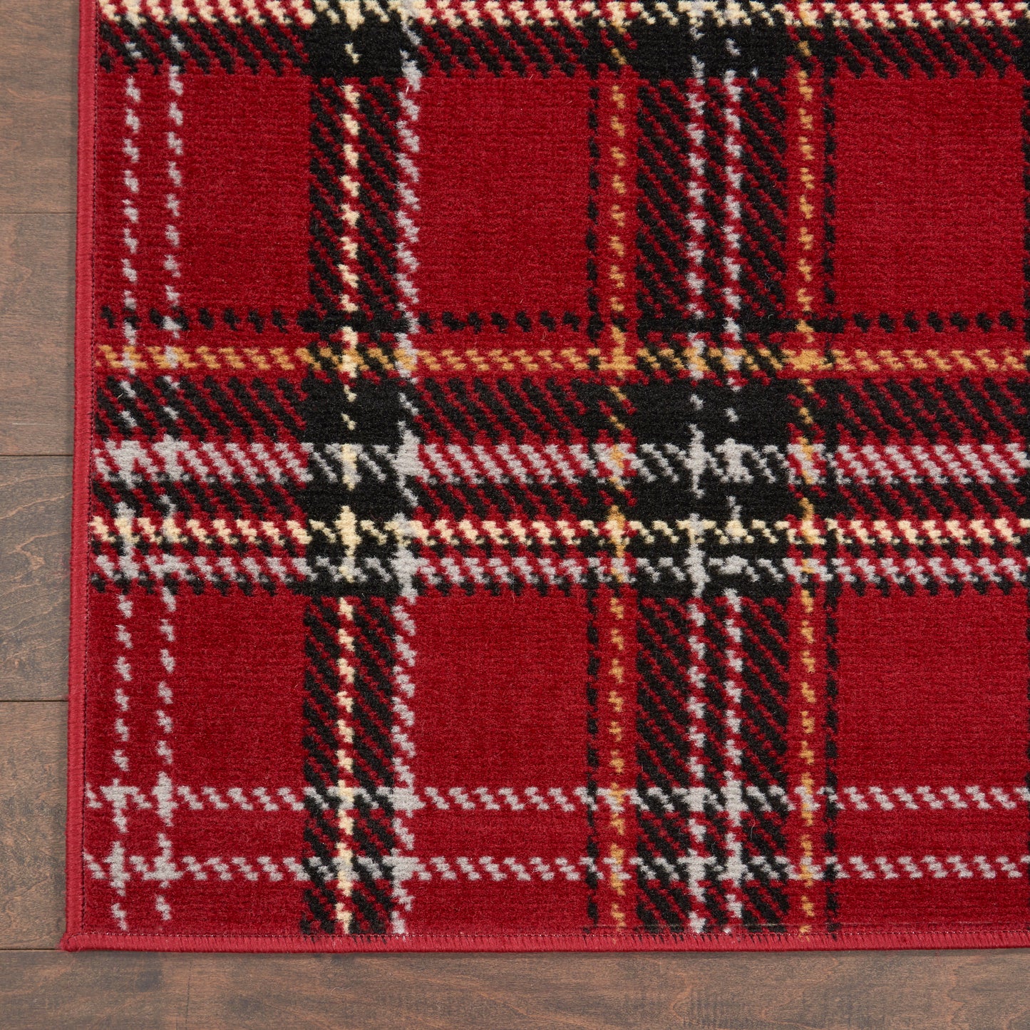 Red plaid woven rectangular rug with black, white & tan stripes on wood floor.