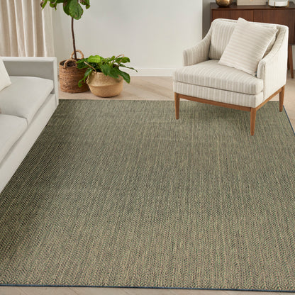 Large textured gray-green woven rug under a beige striped armchair with wooden legs in a bright living room.
