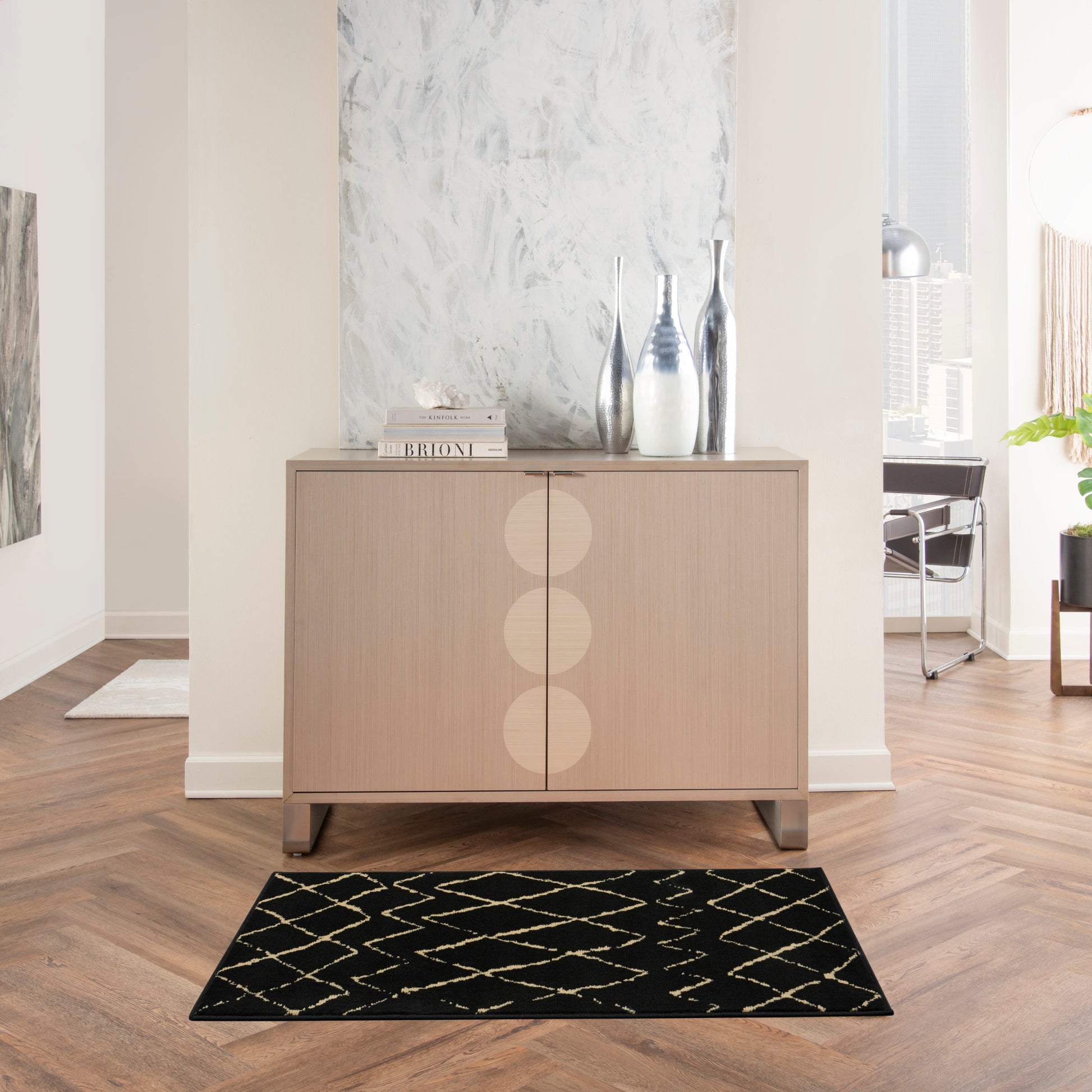 Light wood mid-century sideboard with three circular door accents and metallic vases on top in a bright modern living space.