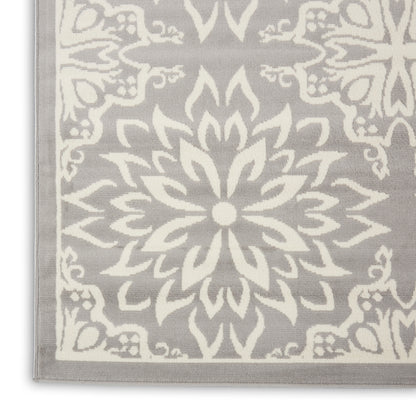 Gray woven rug with a large white mandala floral motif and light border; rectangular rug.