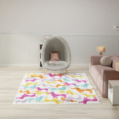 Rectangular rug with multicolor abstract silhouettes on a light floor beside a gray pod chair and pink sofa.