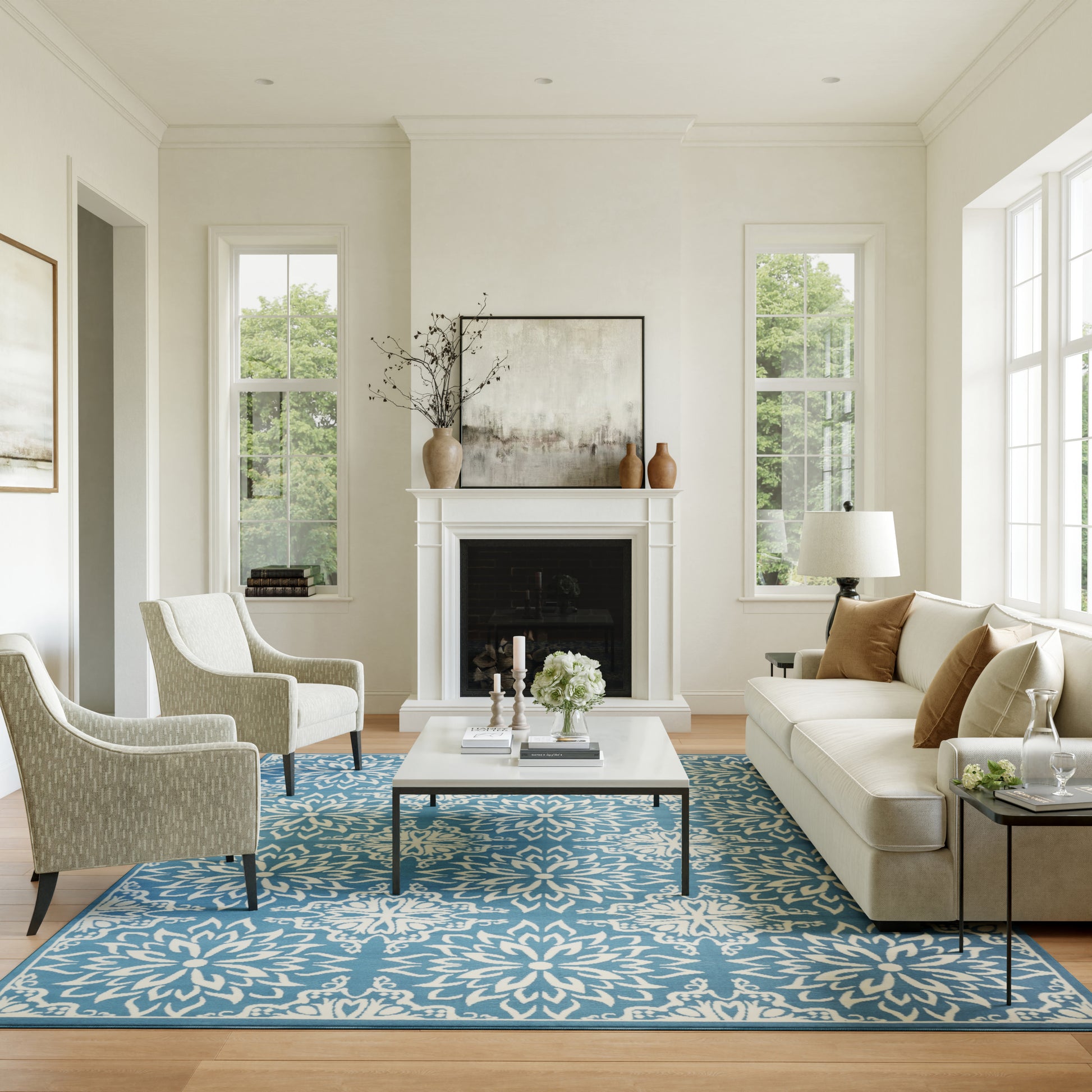Bright living room with white walls, blue floral rug, beige sofa, two armchairs, fireplace and coffee table.