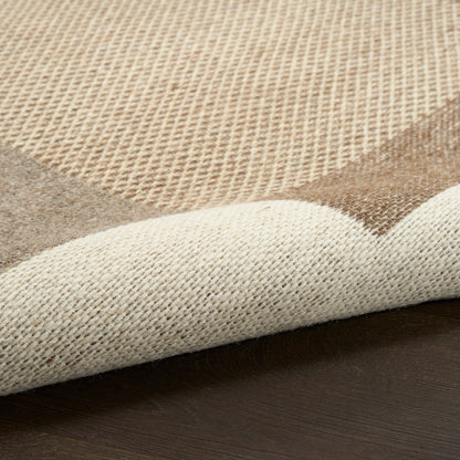 Beige woven area rug with cream and tan geometric pattern, rolled corner on dark wooden floor.