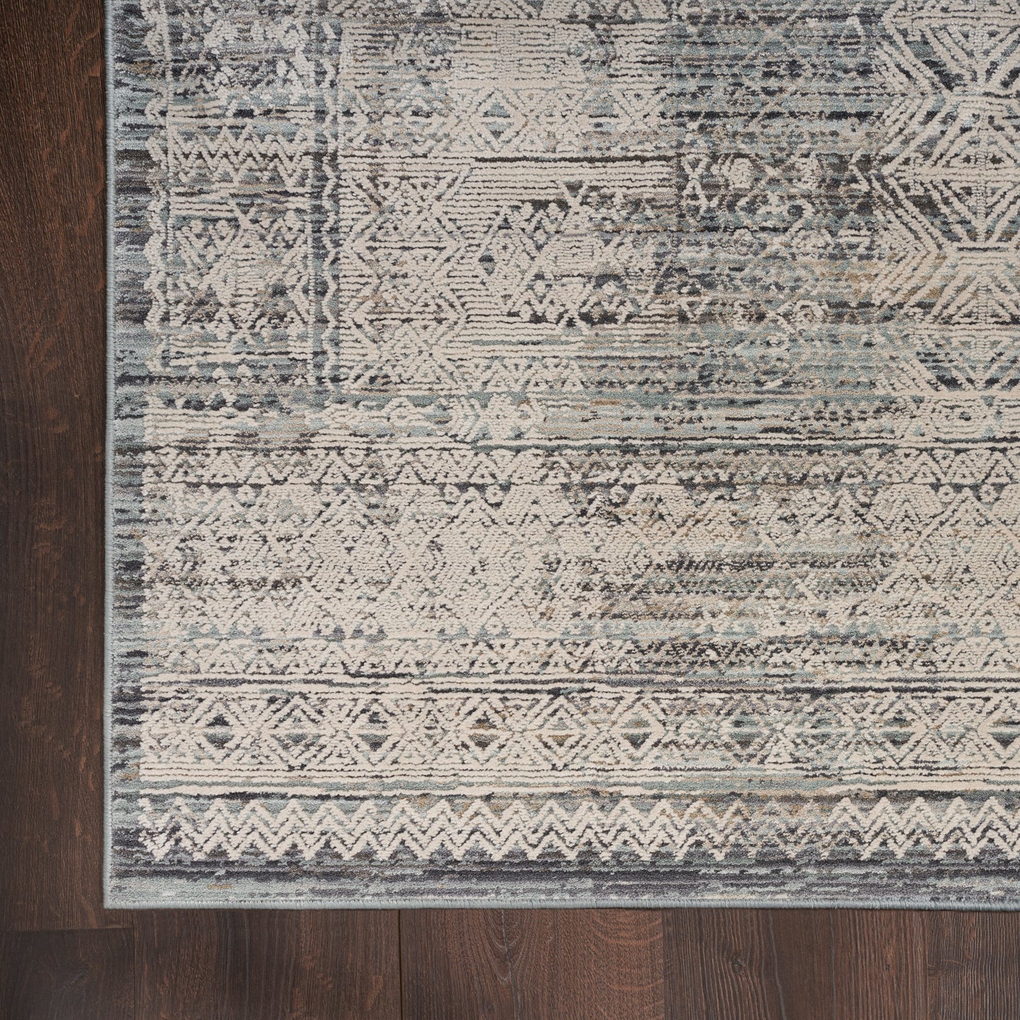 Blue-gray distressed geometric runner rug with tribal motifs and light border on dark wood floor.