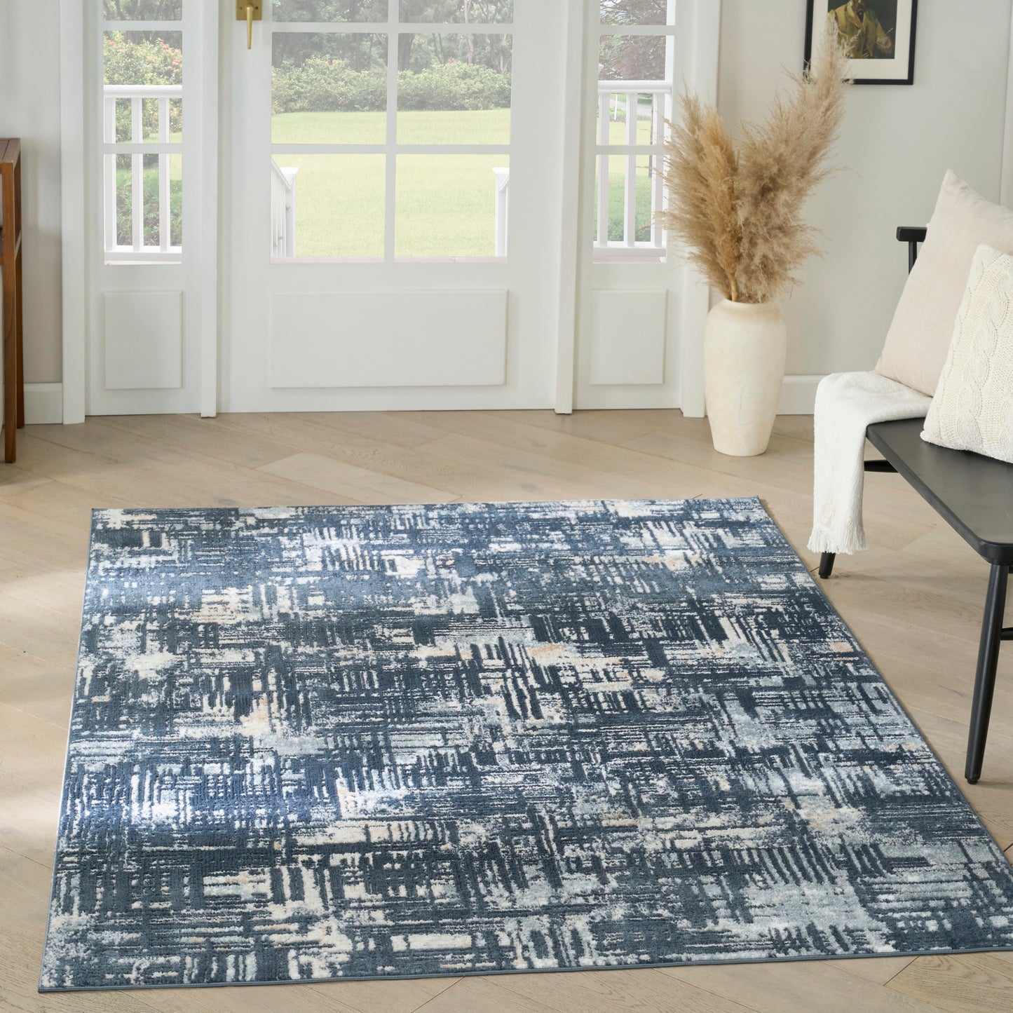Blue and ivory abstract patterned rectangular area rug in a modern living room, soft woven texture on light wood floor.