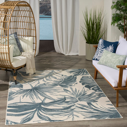 Teal palm-leaf patterned rug on ivory base; woven textile for boho coastal living room decor.