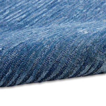 Blue woven rug close-up with raised loop pile and striped texture along edge.