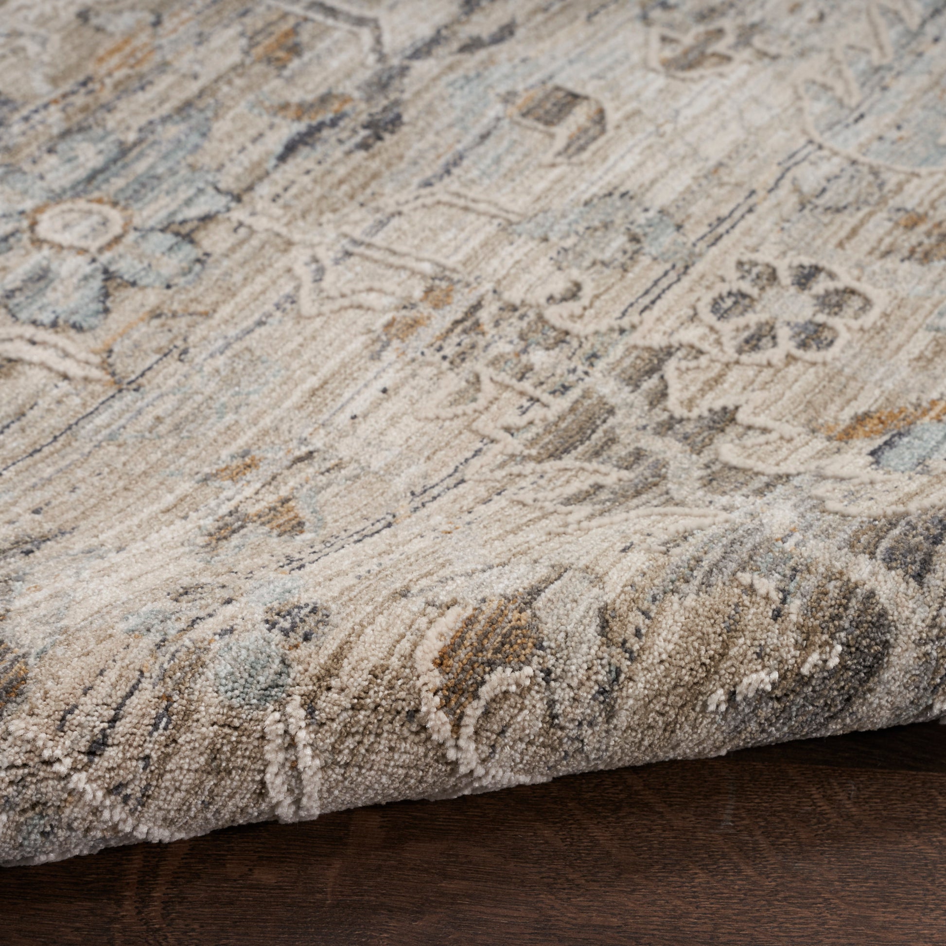 Beige and blue-toned patterned area rug with soft tufted pile and rolled edge, oriental-inspired floral motif.