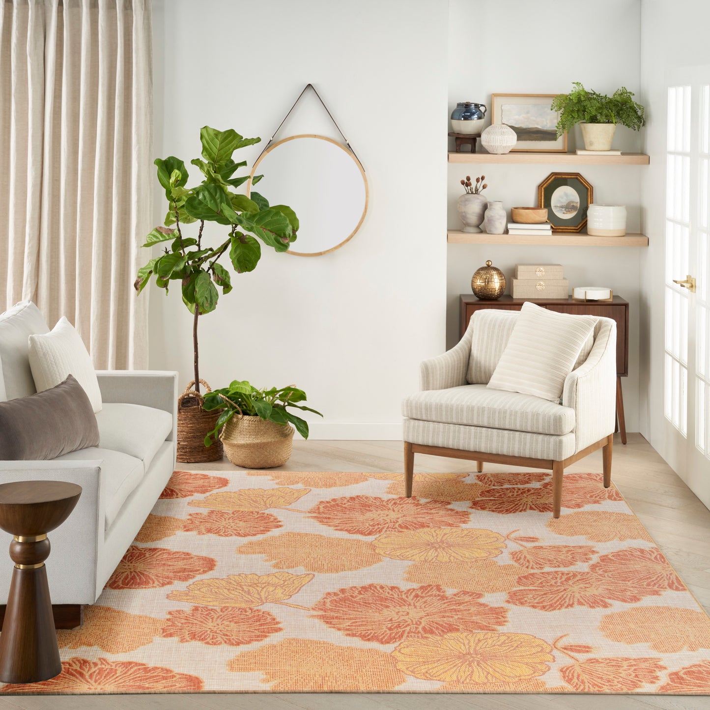 Bright living room with cream sofa, striped armchair, orange floral rug, potted plants, and mid-century shelves.