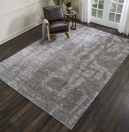 Large gray textured area rug on dark wood floor with a brown quilted armchair, a small side table, plant, and curtains.