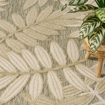 Beige woven rug with cream tropical leaf pattern; potted variegated green-and-cream plant in a wicker planter.