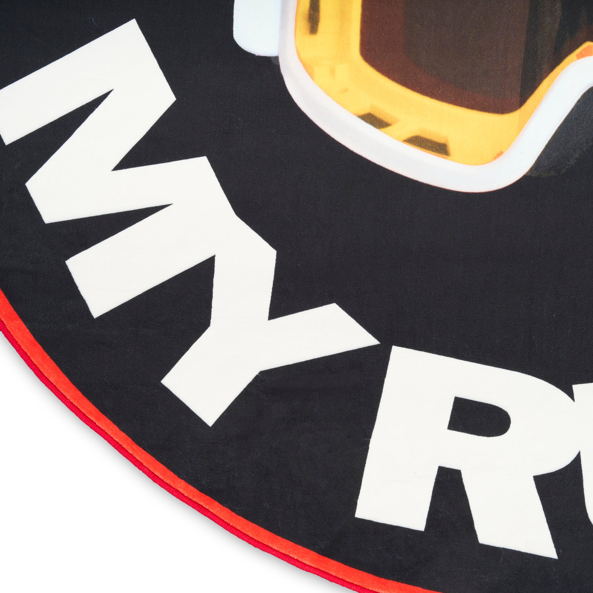 Round black rug with red trim, white bold letters, and partial yellow ski goggles graphic.