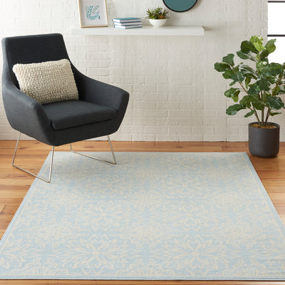 Dark gray modern armchair on pale blue floral rug; white brick wall, potted plant, and shelf decor in cozy living room.