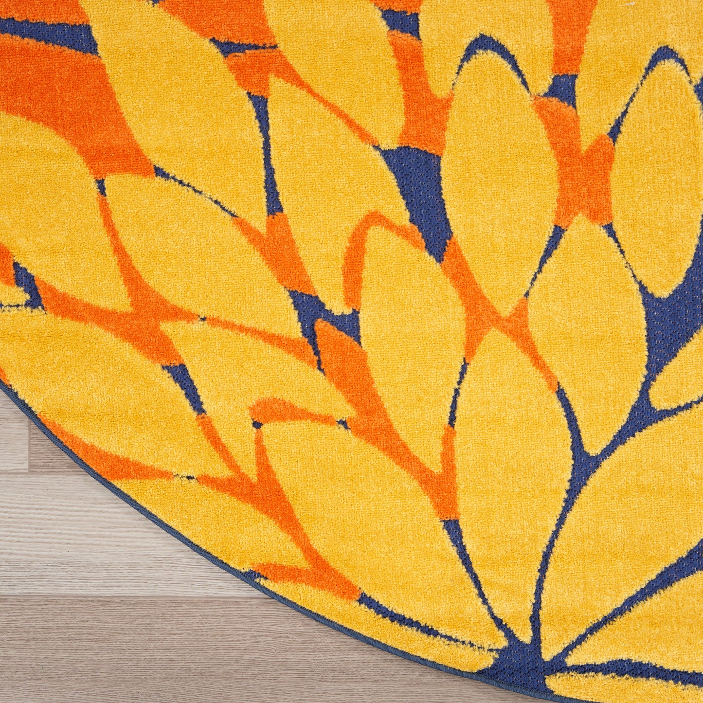 Round rug featuring bold yellow and orange leaf motif on navy blue background; plush textured pile.