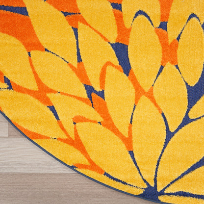 Round rug featuring bold yellow and orange leaf motif on navy blue background; plush textured pile.