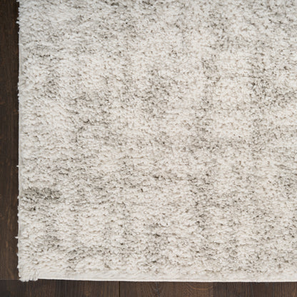 Cream beige shag rug with dense plush pile on dark wooden floor; soft, cozy area rug.