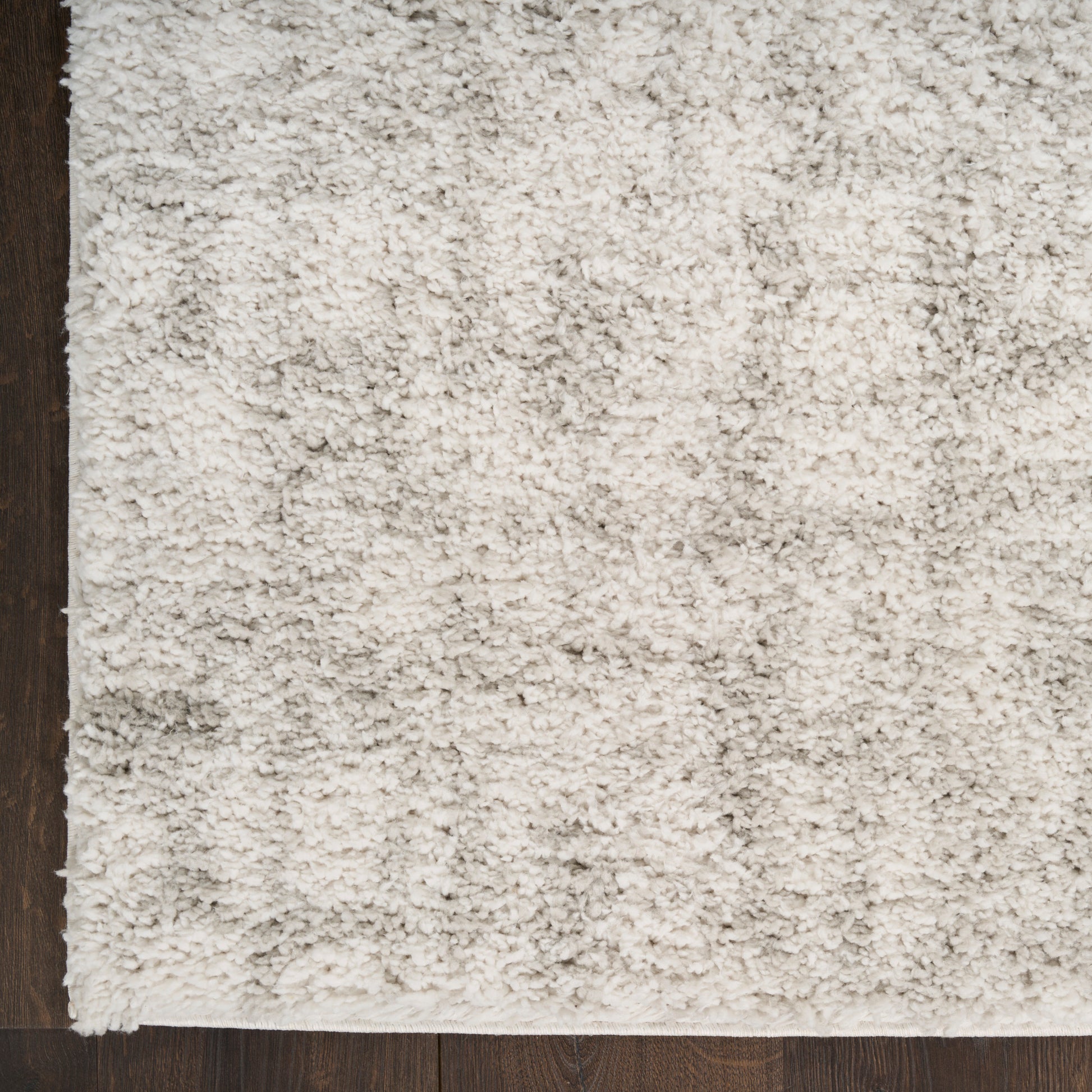 Cream shag area rug with thick plush pile on dark wood floor, rectangular shape.