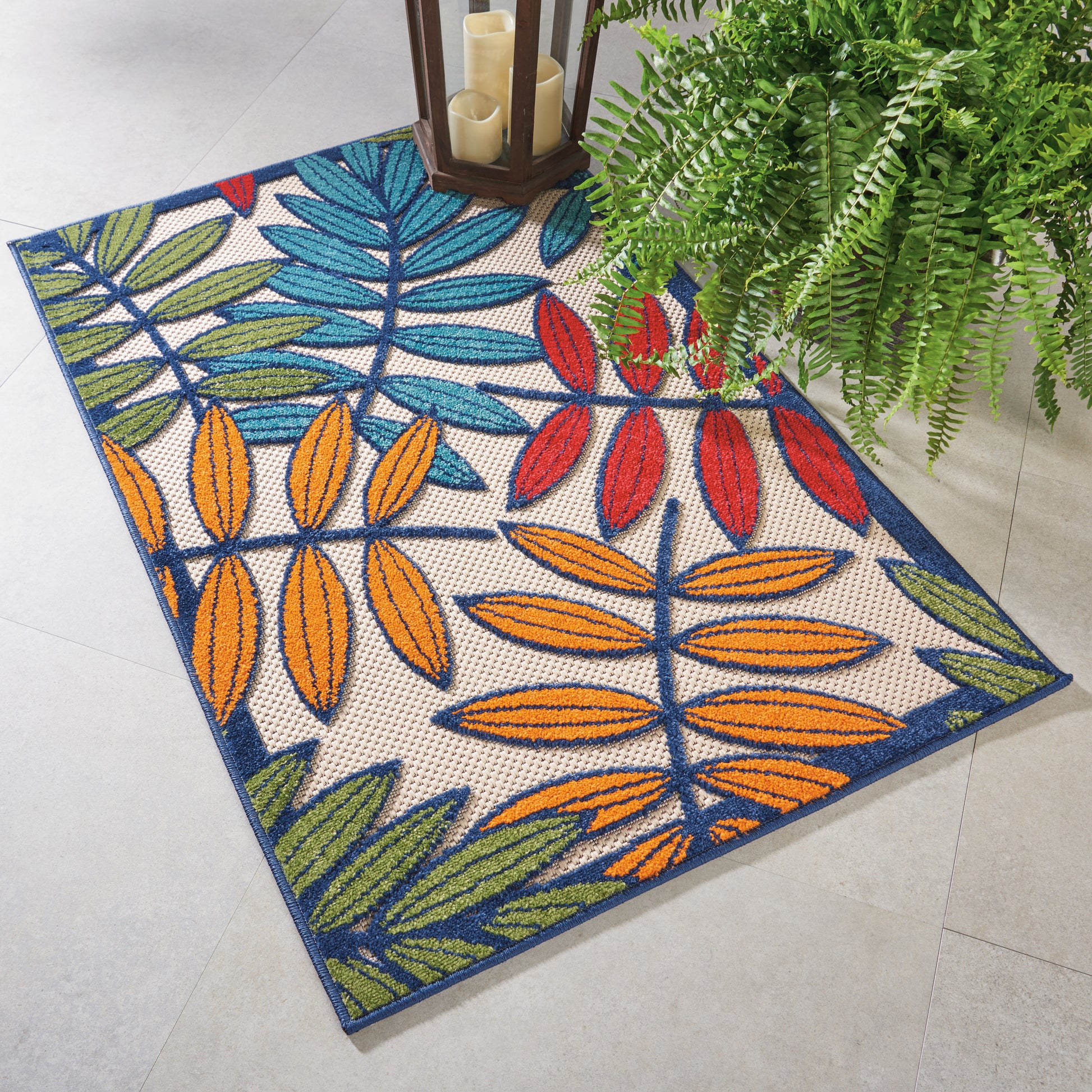Rectangular tropical leaf-pattern rug with orange, yellow, red, blue & green leaves on beige; navy border.