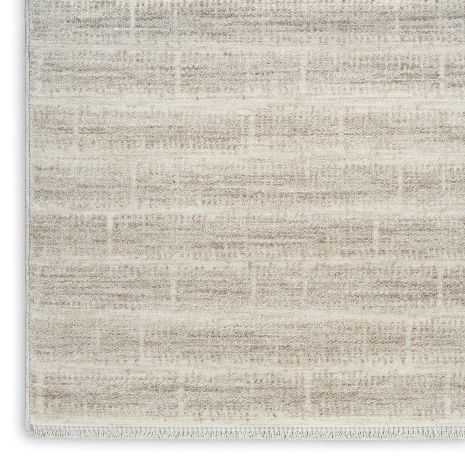 Cream-beige woven rug with subtle geometric pattern and fringe edge; soft, neutral decor piece.