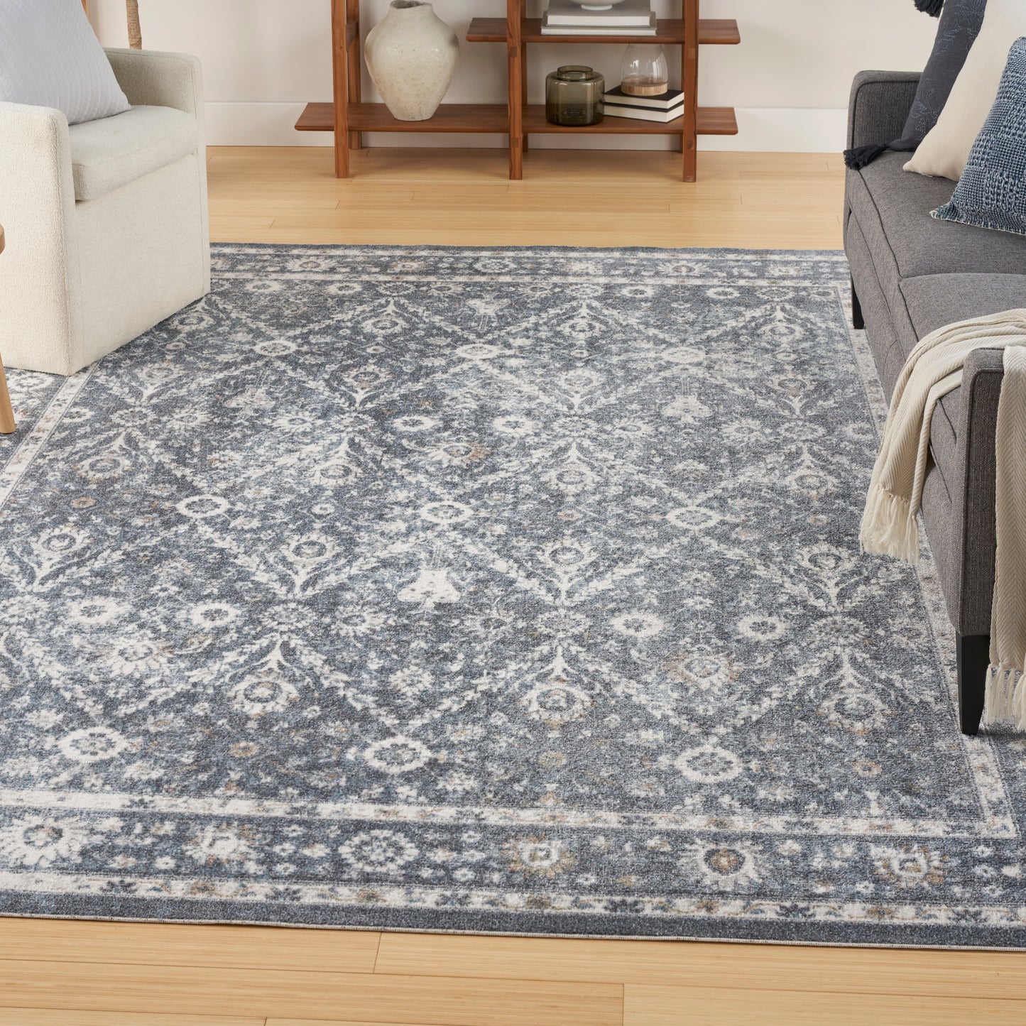 Rectangular blue-gray area rug with ivory damask medallion pattern in a cozy living room.