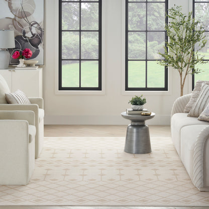 Neutral living room with cream sofas, beige rug, round metallic side table, potted plant, and black-framed windows.