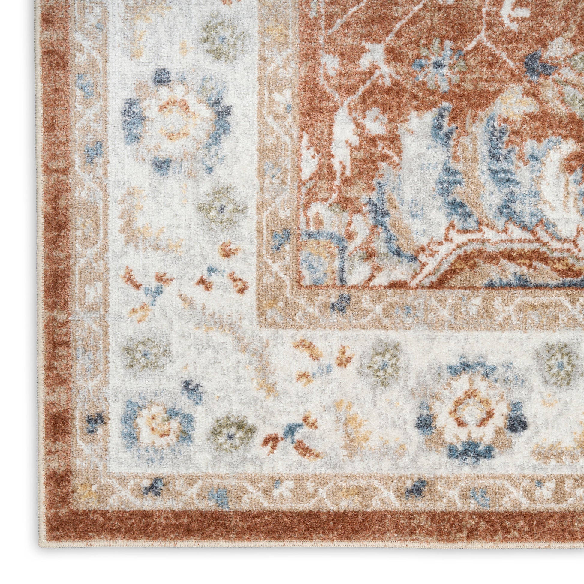 Close-up of an ornate patterned rug with rust-orange & ivory field, pale blue floral accents, and decorative border.