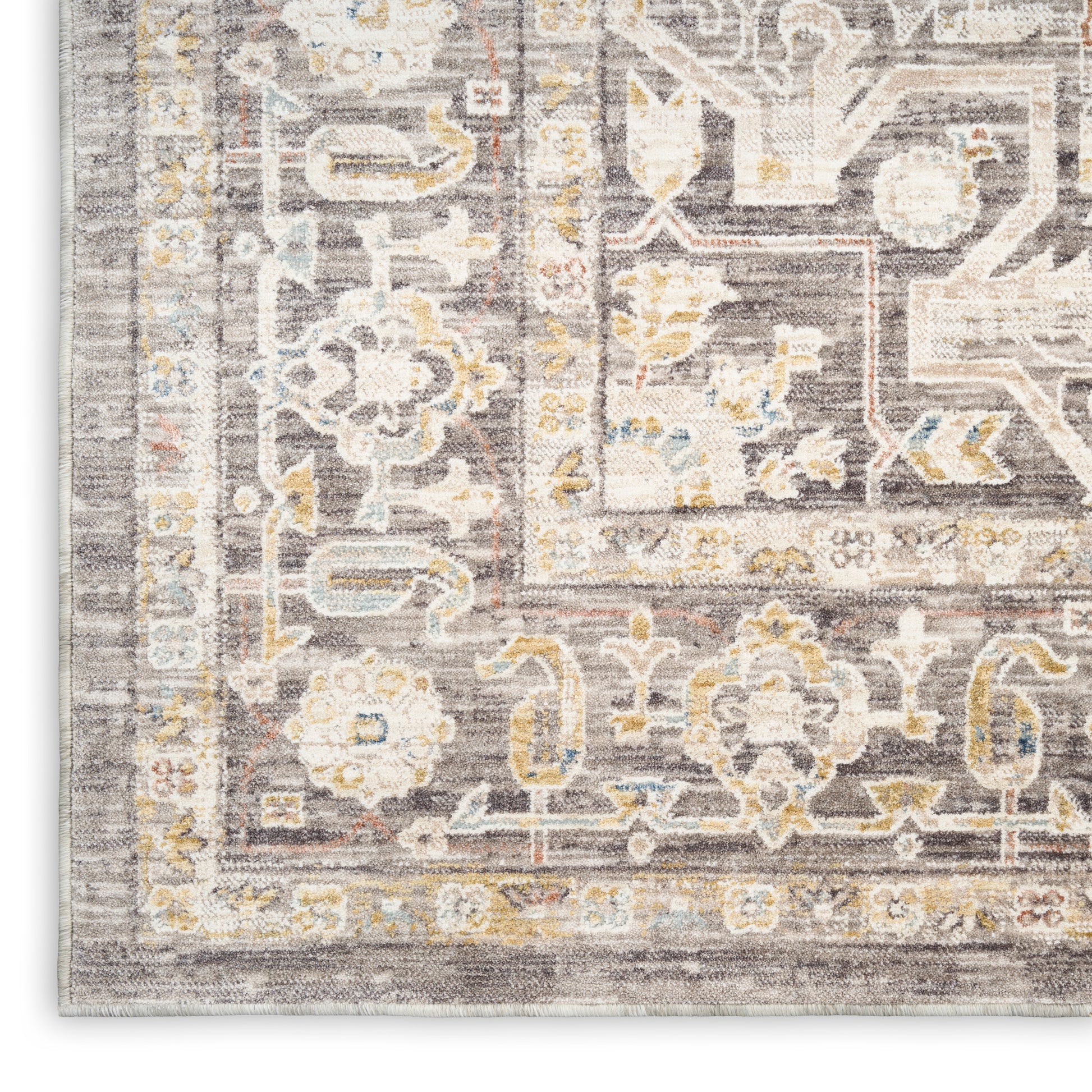 Close-up of a gray distressed oriental rug with ivory floral medallions and pale yellow and blue accents.