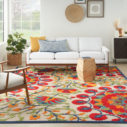 Vibrant floral area rug in red, yellow, blue and green on cream; modern living room with white sofa and wooden coffee table.