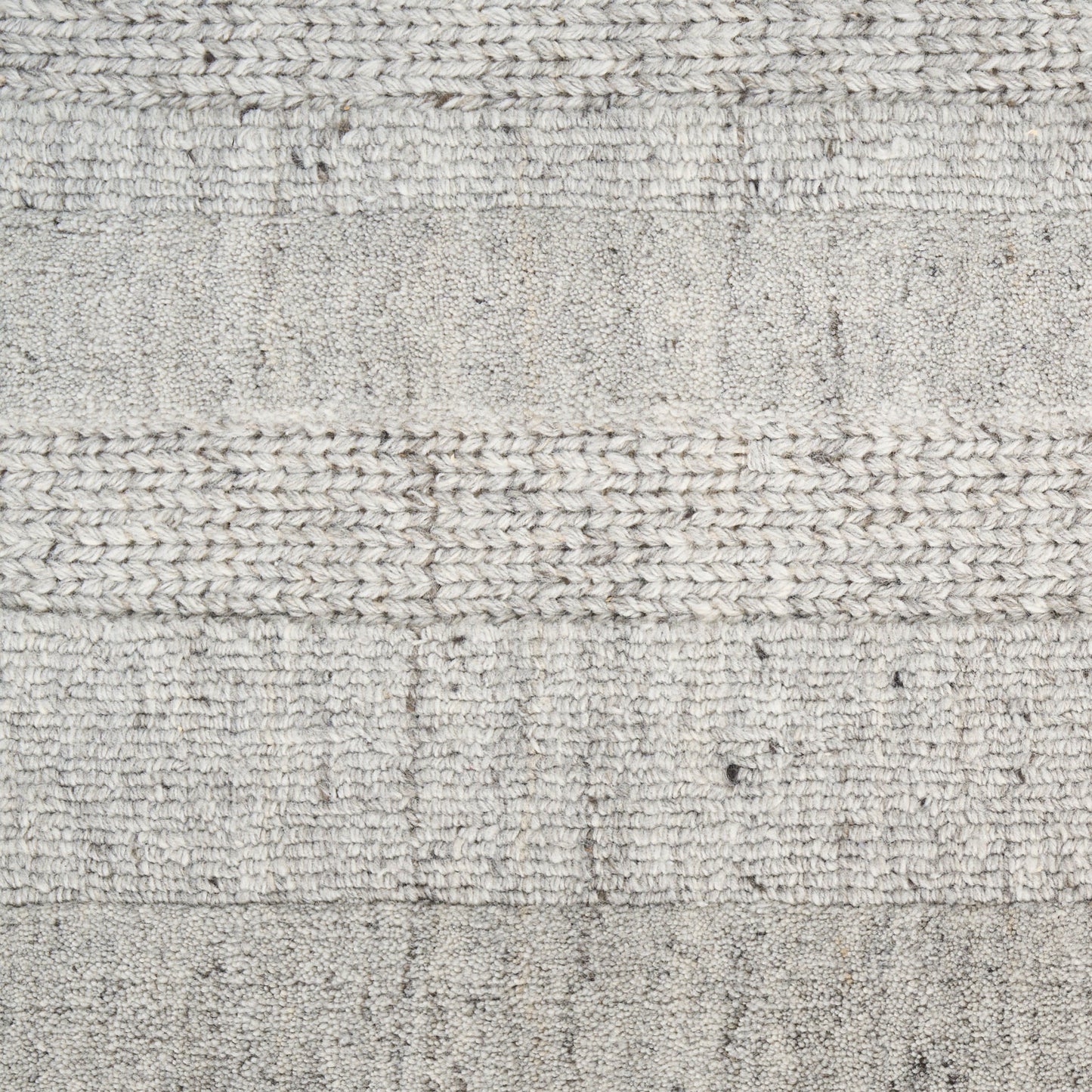 Close-up of a light gray knitted rug with alternating textured stripes and subtle speckled fibers.