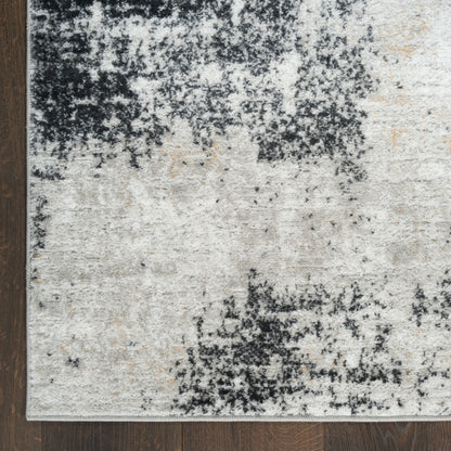 Rectangular plush area rug in cream, beige & charcoal with abstract distressed pattern on dark wood floor.