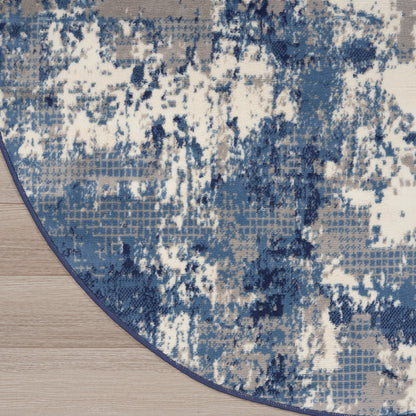 Round rug featuring an abstract blue and white pattern with a dark blue edge on a light wood floor.
