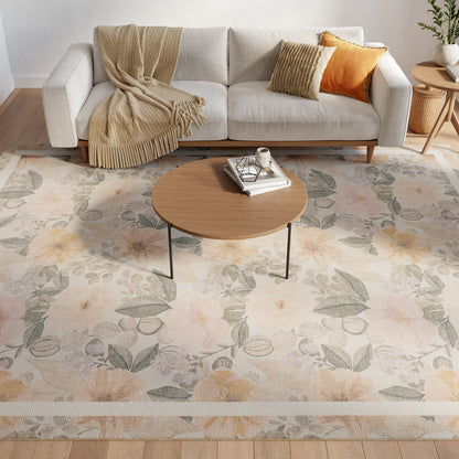 Cozy living room: beige sofa with tan throw and orange pillows, round wood coffee table, on a pastel floral rug.