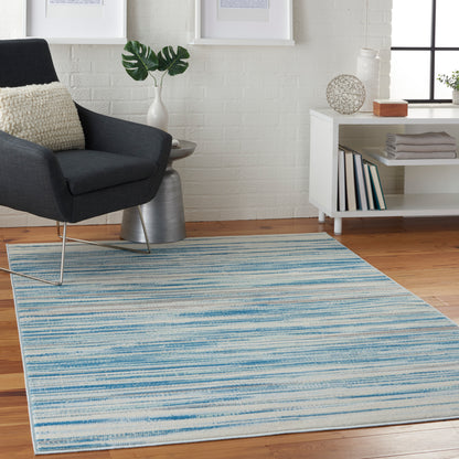 Rectangular blue striped area rug on wood floor with a dark grey armchair and white modern living room setup.