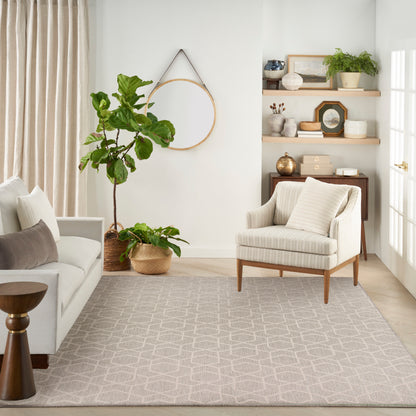 Neutral living room with gray sofa, striped beige armchair, tall fiddle-leaf fig plants, woven rug, and open shelving.