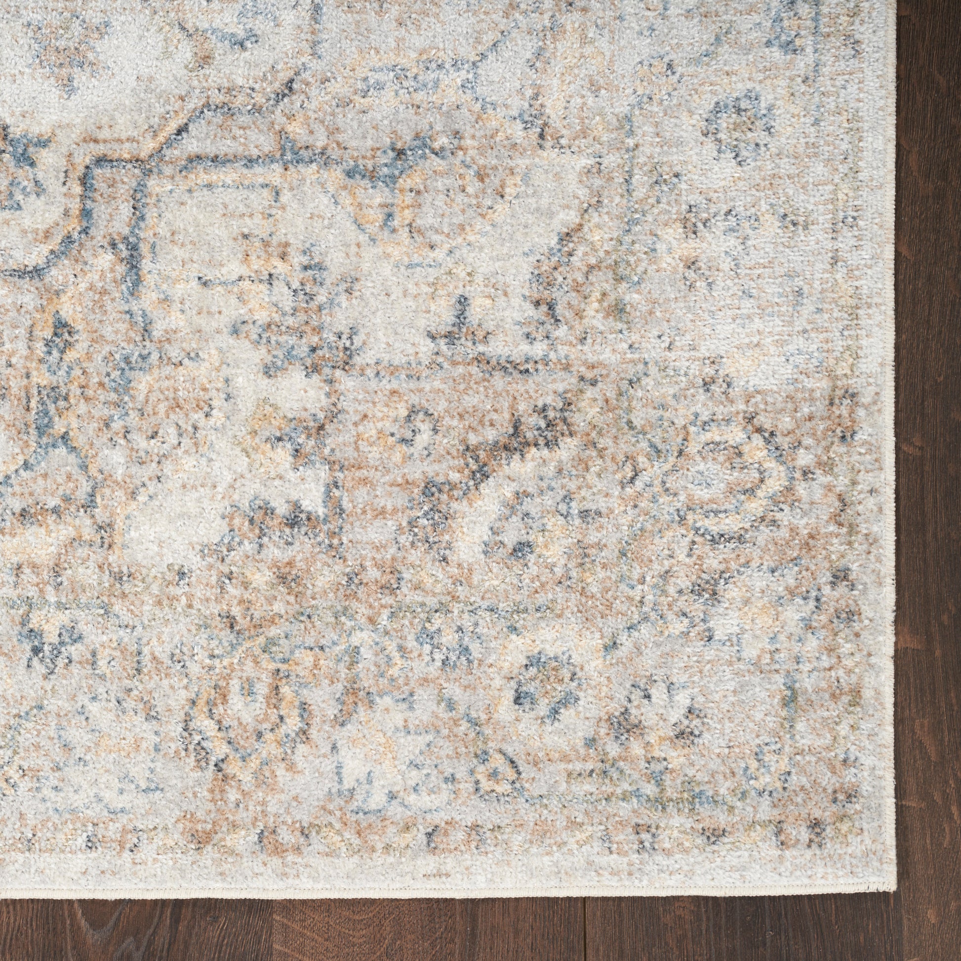 Distressed cream & blue oriental rug with tan accents, rectangular shape, classic floral motifs, on dark hardwood.