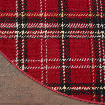 Red plaid circular rug with bold tartan pattern of black, white, and yellow on wood floor.
