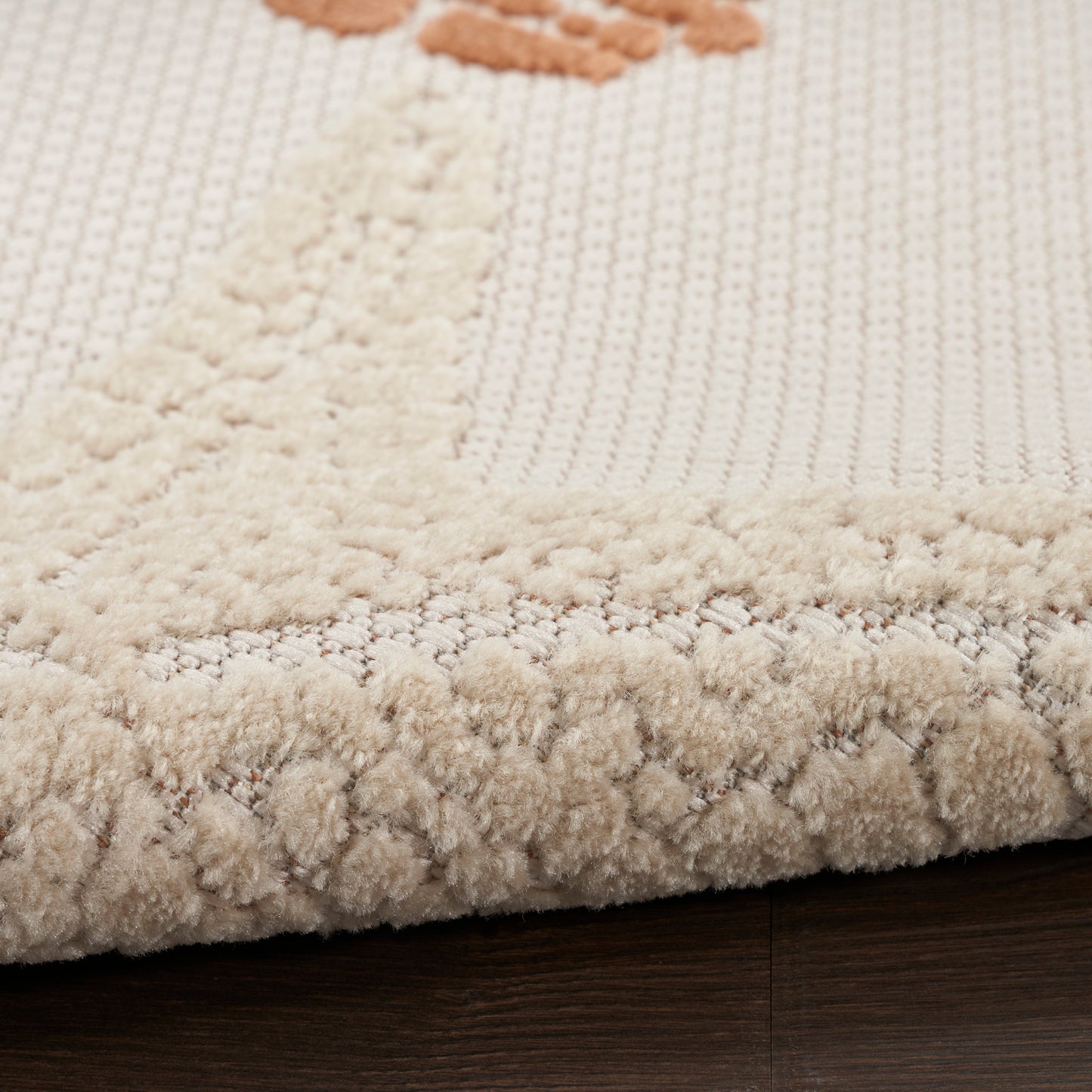 Cream outdoor rug with a thick plush border and textured knit field.