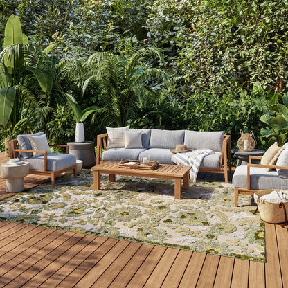 Outdoor 6' x 9' rug with a gray patterned design, laid out in a greenery-filled outdoor setting.