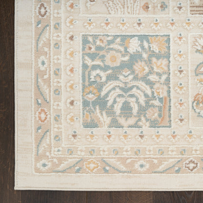 Traditional oriental rug with a blue central field of floral motifs and cream/beige border on dark wood floor.