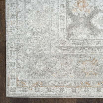 Soft, plush light gray area rug with ivory distressed pattern and tan accents on a dark wooden floor.