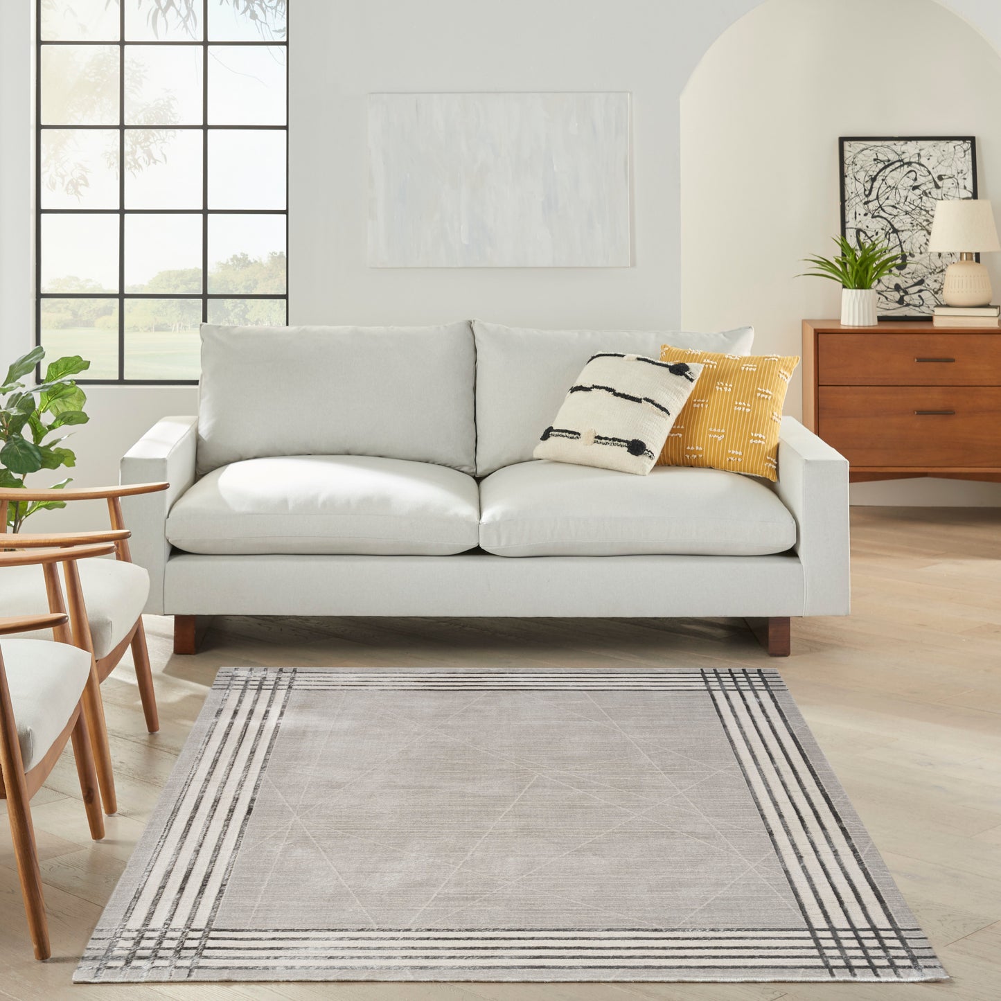 Gray striped rug in a bright living room, complemented by a light gray sofa with mustard yellow and cream striped pillows.