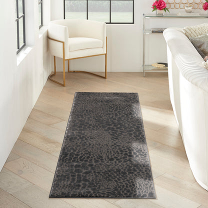 Dark gray textured runner rug on light wood floor in a bright living room with a white armchair and gold metal frame